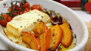 In einer weißen Keramikform liegen Kürbisspalten, Fetakäse und gegrillte Tomaten