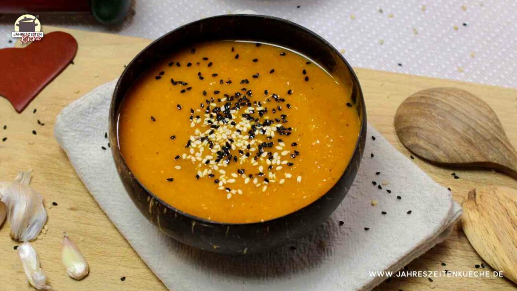 Eine schnelle Kürbissuppe in einer braunen Kokoschale ist mit Sesam und Schwarzkümmel bestreut