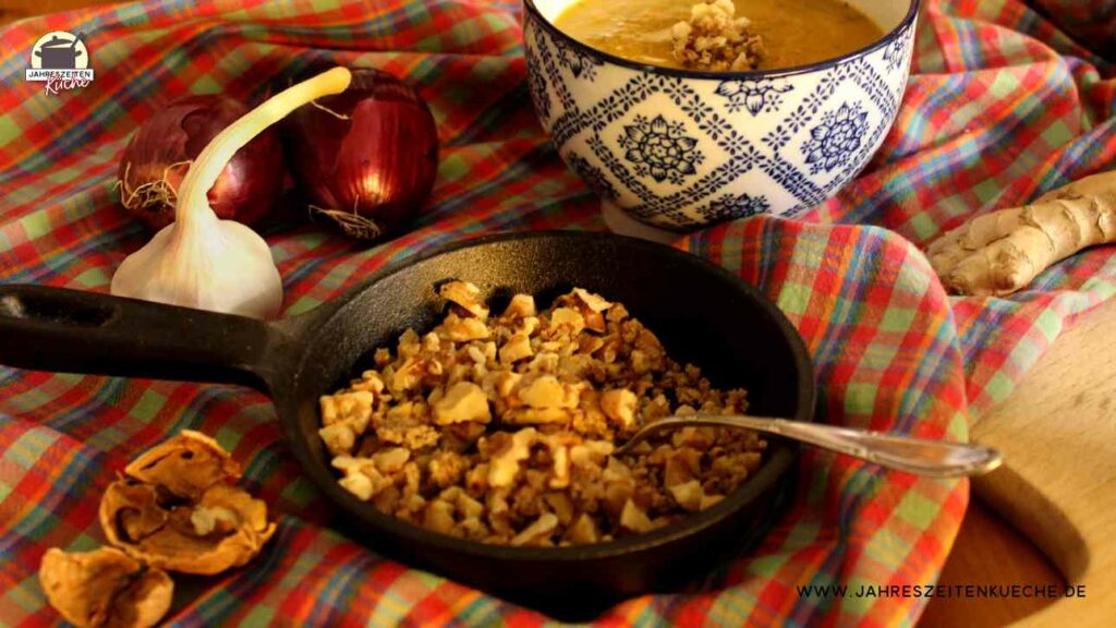 Eine kleine Gusseisen-Pfanne mit Walnuss-Crunch, in dem ein Teelöffel steckt.