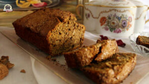 Ein angeschnittener Karotten-Kuchen mit Walnüssen liegt auf einem Glastablett