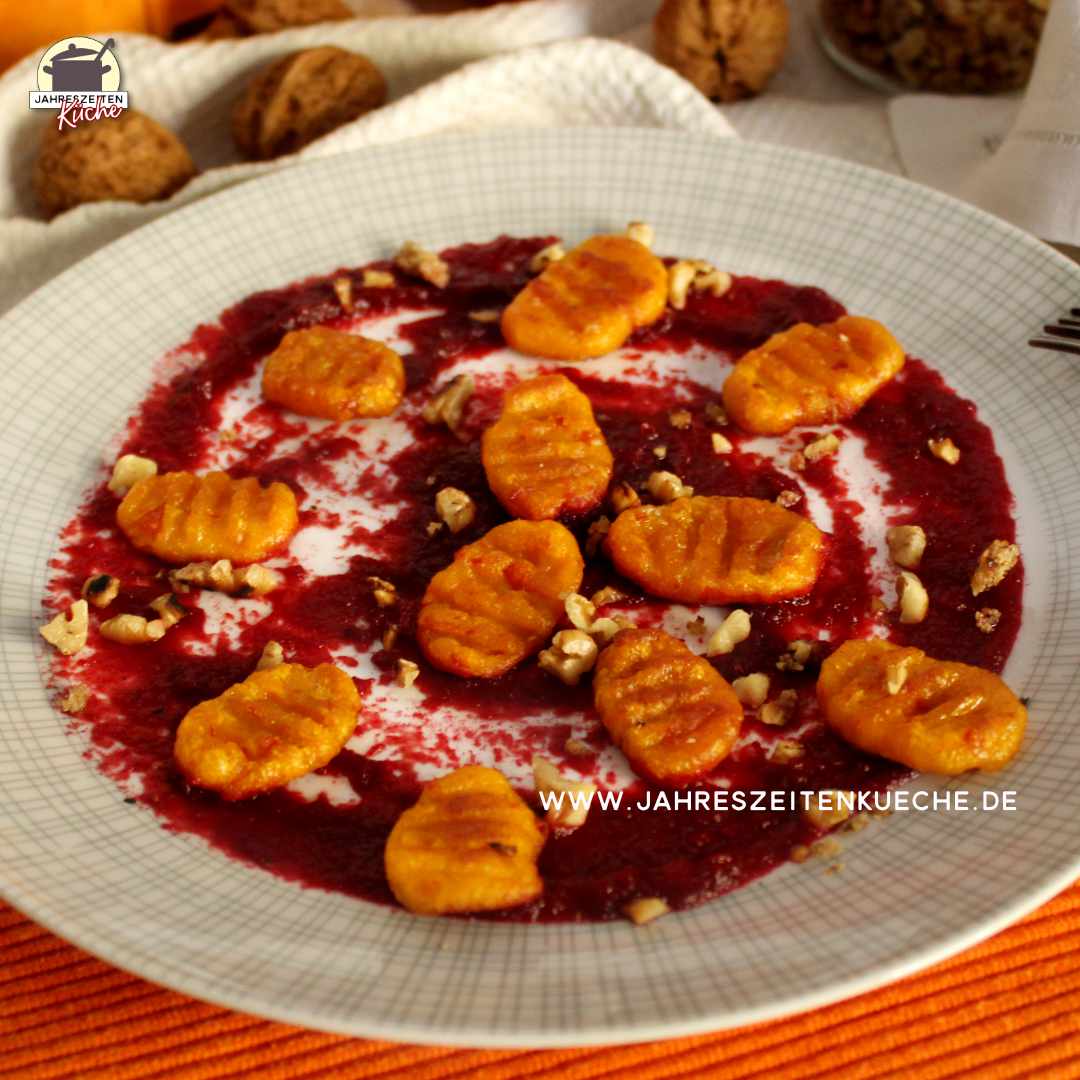 Ein Teller mit Kürbis-Gnocchi und karamellisierten Walnüssen auf Rote-Bete-Aufstrich