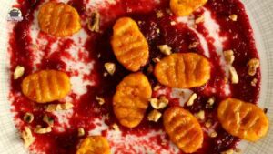 Ein Teller mit Kürbis-Gnocchi und karamellisierten Walnüssen auf Rote-Bete-Aufstrich