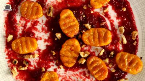 Ein Teller mit Kürbis-Gnocchi und karamellisierten Walnüssen auf Rote-Bete-Aufstrich