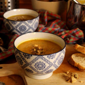 Zwei Schälchen mit Karotten-Zucchini-Suppe stehen auf einem Holztisch