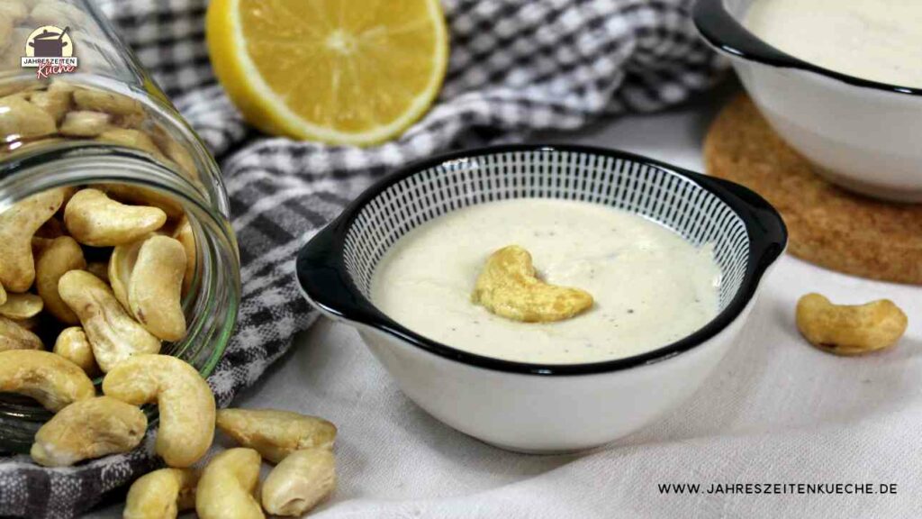 Neben einem Schälchen mit Cashewcreme liegt ein Glas mit Cashewnüssen