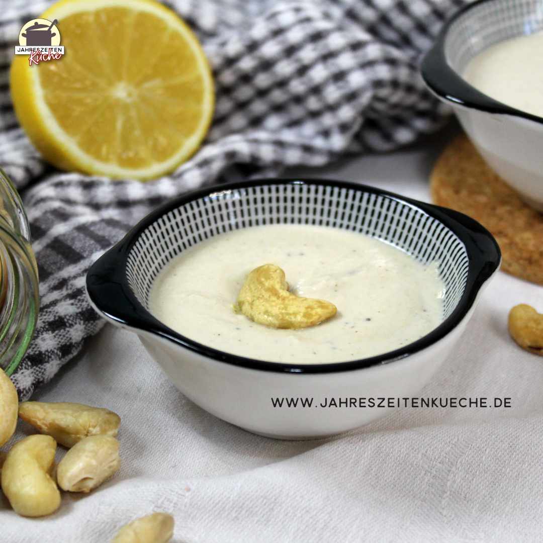 Neben einem Schälchen mit Cashewcreme liegt ein Glas mit Cashewnüssen