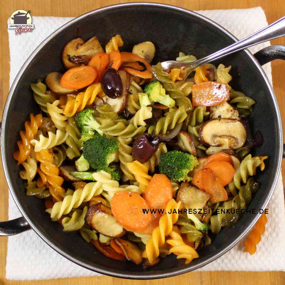 Eine Gemüse-Nudelpfanne mit Brokkoli, Champignons und Karotten in der Draufsicht