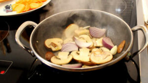 Zwiebeln und Champignons werden in einer Pfanne angebraten