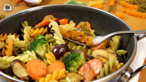 Angebratenes Gemüse mit bunten Spirelli-Nudeln in einer Pfanne