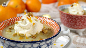 Petersilienwurzelsuppe mit Orange, Schlagsahne und karamellisierten Walnüssen in einer kleinen Suppentase