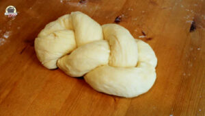 Geflochtener Dinkel-Hefezopf liegt auf einem Holztisch