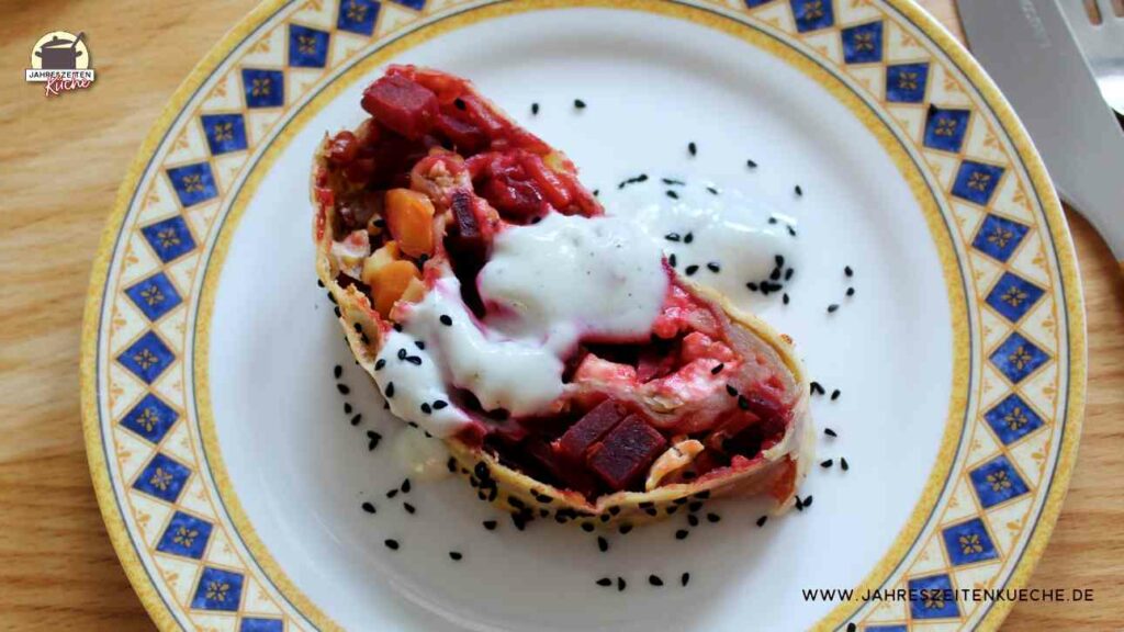 In der Draufsicht ist ein Stück Rote-Bete-Strudel zu sehen, das auf einem Teller mit blaugelbem Rand liegt