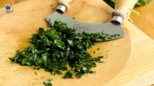 Frisch gehackter Bärlauch auf einem Holzbrett mit Wiegemesser