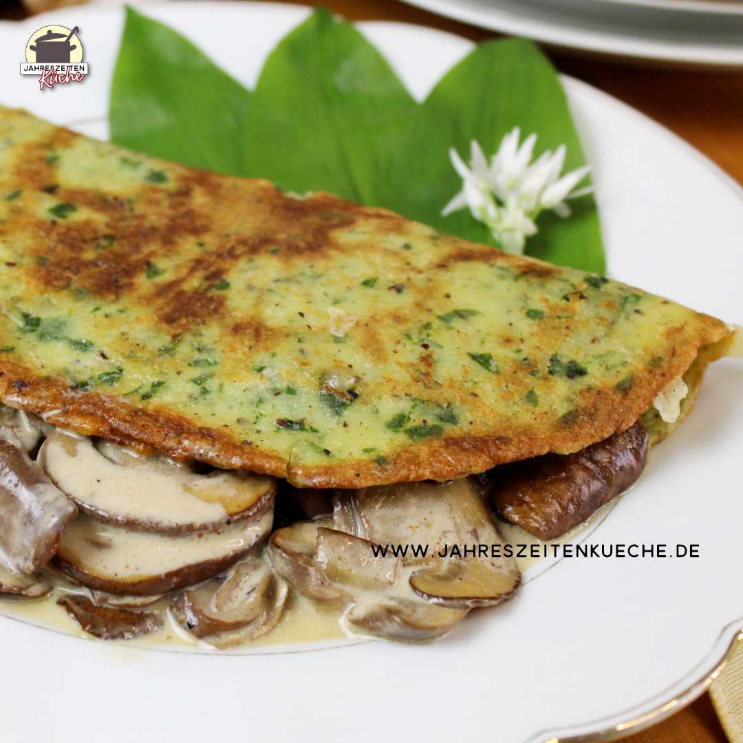 Ein Bärlauch-Pfannkuchen mit Champignons ist auf einem weißen Teller mit frischen Bärlauch-Blättern angerichtet