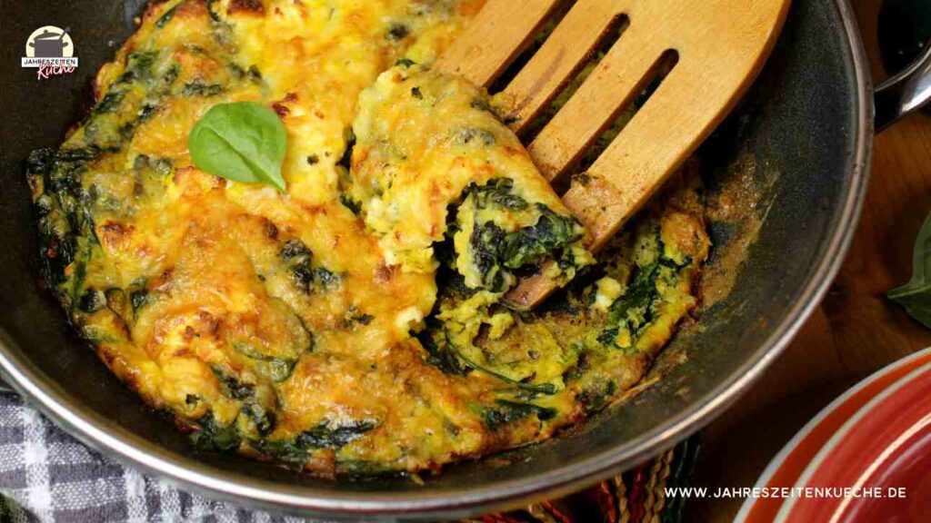 Gebackenes Spinat-Frittata in einer Pfanne mit Holzlöffel