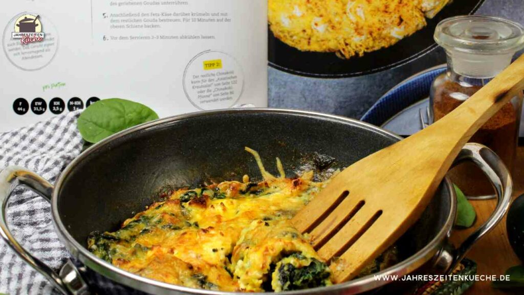 Eine Pfanne mit Spinat-Frittata. Im Hintergrund steht das Kochbuch von Dinah Stricker "Keto quick!"