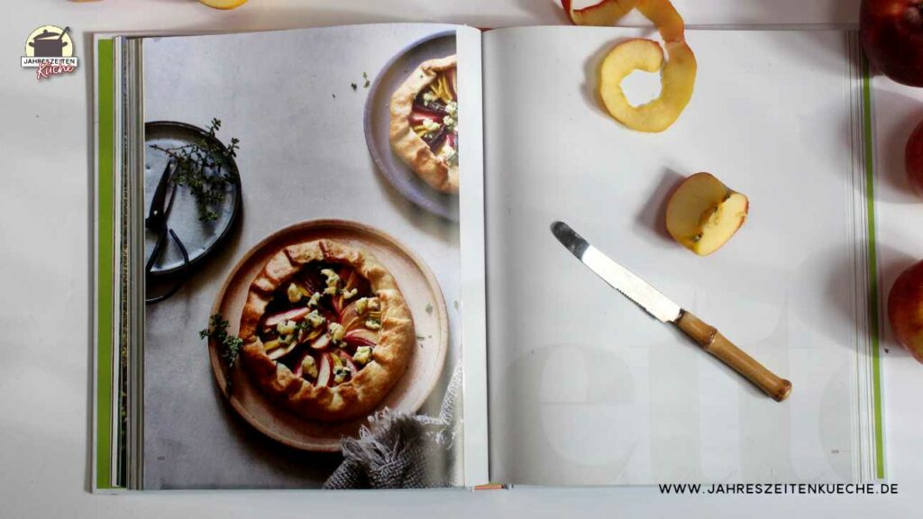 Doppelseite aus dem großen Buch vom Apfel. auf der linken Seite ist eine Minigalette mit Äpfeln, Bunte Bete und Blauschimmelkäse zu sehen, auf der rechten Seite liegt eine geschälter Apfel.