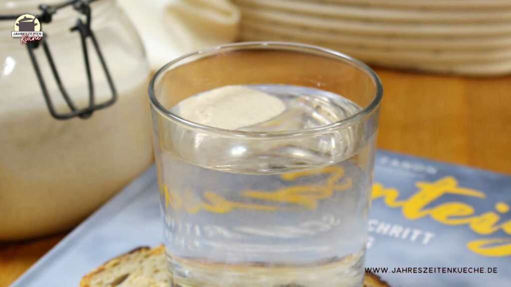 Etwas Sauerteig schwimmt in einem Glas an der Wasseroberfläche