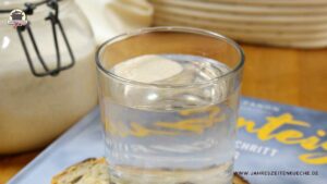 Etwas Sauerteig schwimmt in einem Glas an der Wasseroberfläche