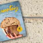 Das Backbuch Sauerteig von Valérie Zanon im Vordergrund. Im Hintergrund sind zwei Brothälften, die aufeinander liegen.