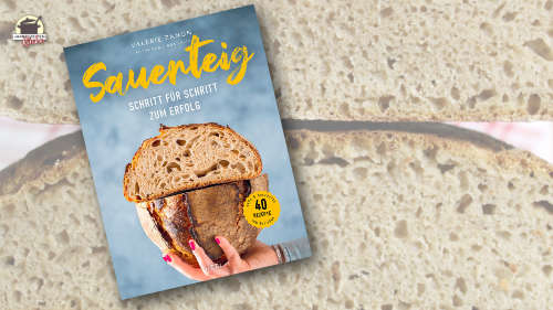 Das Backbuch Sauerteig von Valérie Zanon im Vordergrund. Im Hintergrund sind zwei Brothälften, die aufeinander liegen.